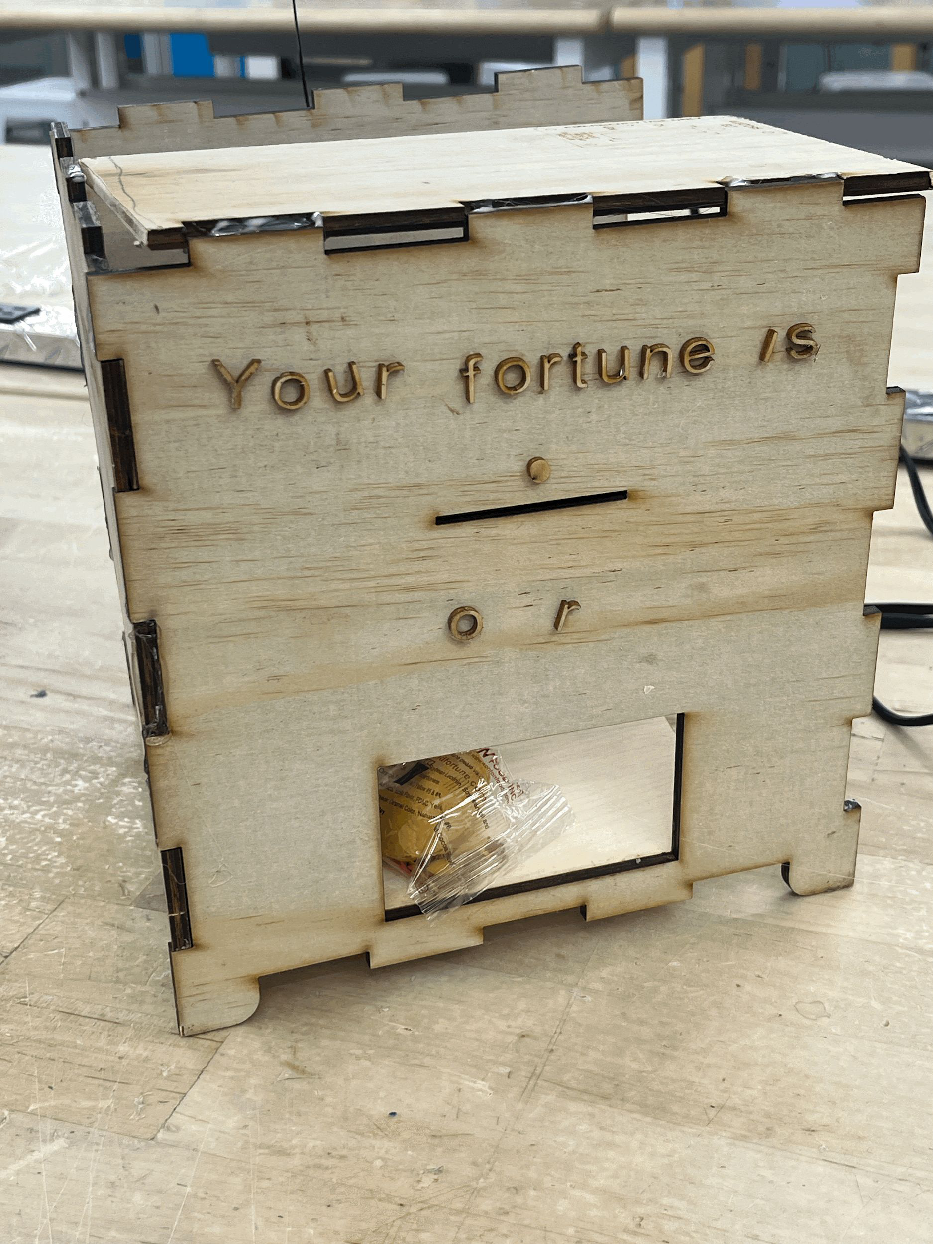 Laser-cut plywood kiosk front with the words Your fortune is engraved